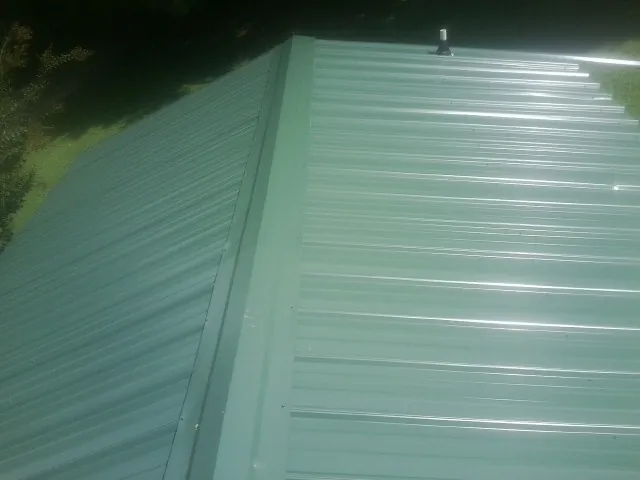 New green metal panels meeting at the ridge of a roof — Flat Roof Repair work by our crew in Randall