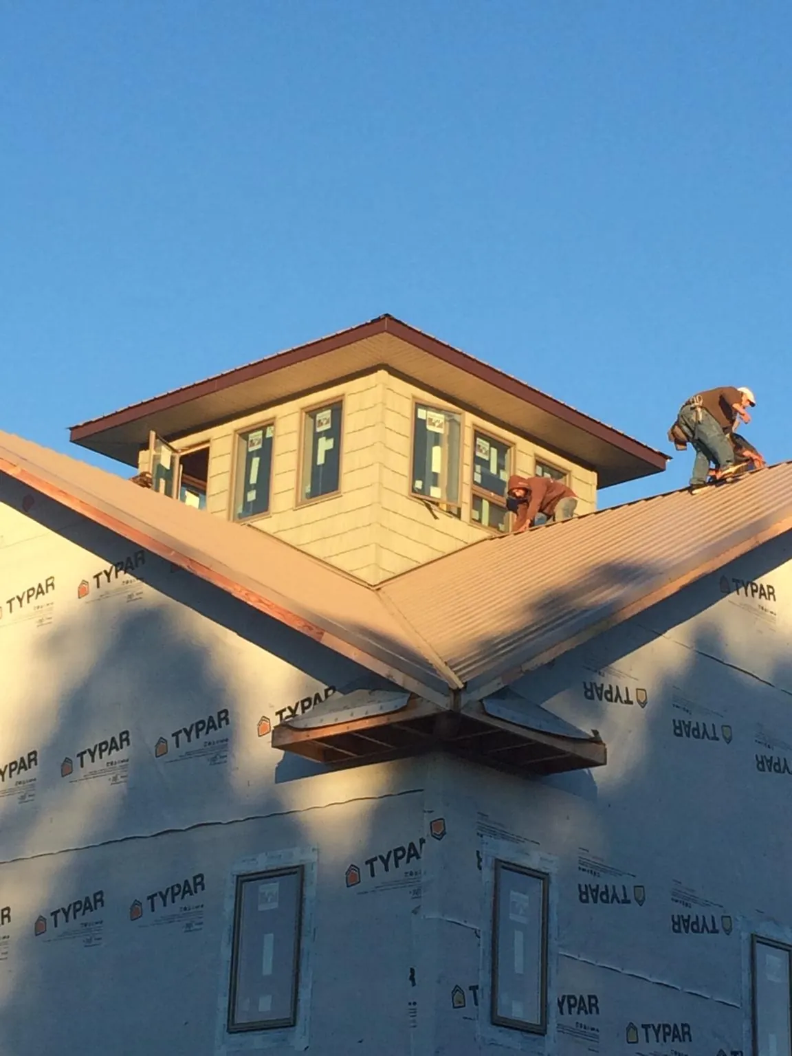 Roofers working around a rooftop cupola on a new metal roof at sunset — Roof Waterproofing in Randall by Roofing Brothers